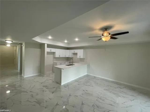 Kitchen featuring light marble finish floors, a peninsula, white cabinets, a ceiling fan, and recessed lighting