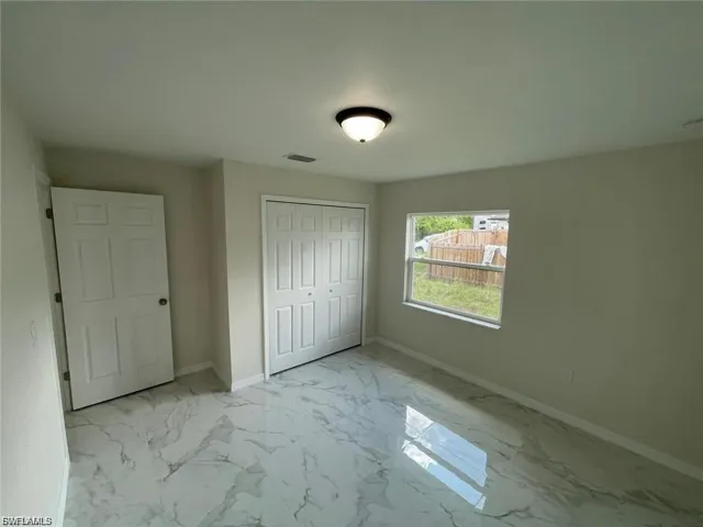Unfurnished bedroom featuring light marble finish floors and a closet