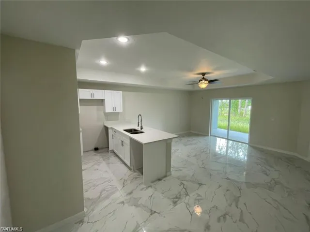 Kitchen with a peninsula, white cabinets, light marble finish floors, recessed lighting, and light stone counters