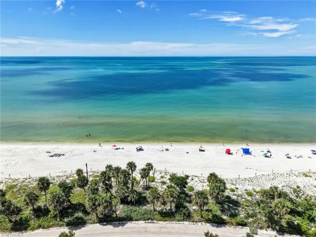 Fenced tennis and pickleball courts situated on a waterfront lot with manicured lawn and mature landscaping