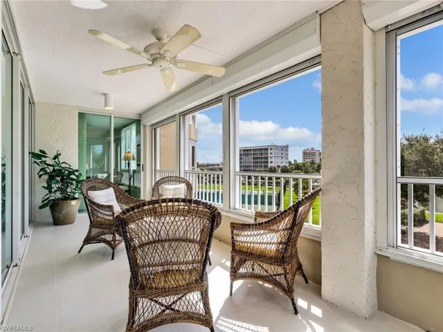 Enclosed porch featuring expansive floor-to-ceiling glass wall panels, large-format tile flooring, and a ceiling-mounted fan