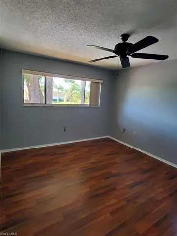 Spare room with ceiling fan, dark wood-style flooring, and a textured ceiling