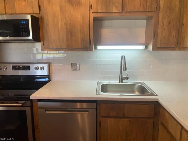 Kitchen with stainless steel appliances, wood finish cabinetry, and decorative backsplash