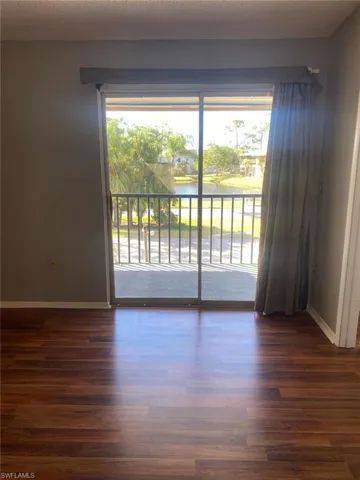 Empty room with a water view, dark wood-style floors, and a textured ceiling