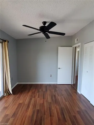 Unfurnished bedroom with a ceiling fan, dark wood-style floors, a textured ceiling, and a closet