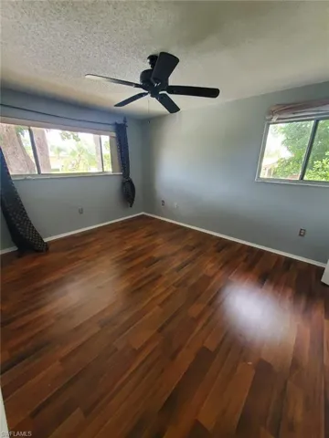 Unfurnished room featuring a textured ceiling, dark wood finished floors, and a ceiling fan