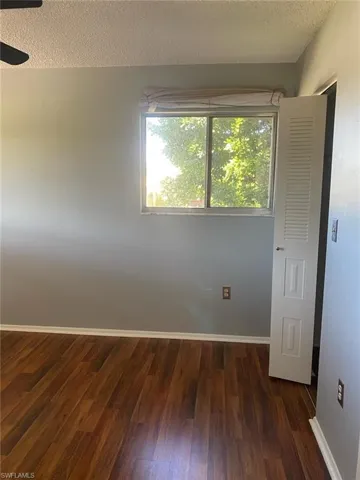 Empty room featuring dark wood-style flooring and a textured ceiling