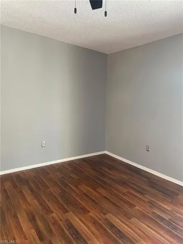 Empty room featuring dark wood-style floors and a textured ceiling