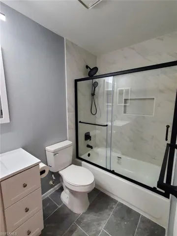 Bathroom with vanity and bath / shower combo with glass door