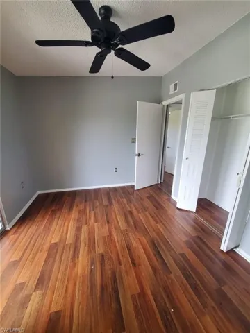Unfurnished bedroom featuring dark wood-style flooring, a ceiling fan, a textured ceiling, and a closet