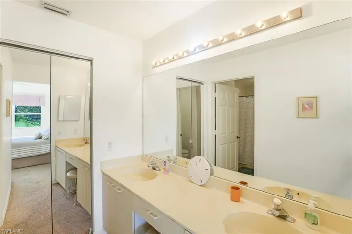 Bathroom with double vanity, connected bathroom, light colored carpet, and curtained shower