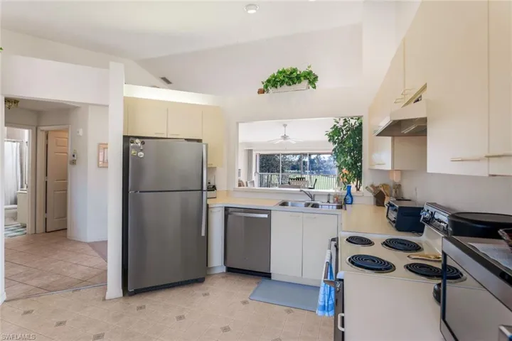 Kitchen with appliances with stainless steel finishes, light countertops, under cabinet range hood, cream cabinets, and ceiling fan
