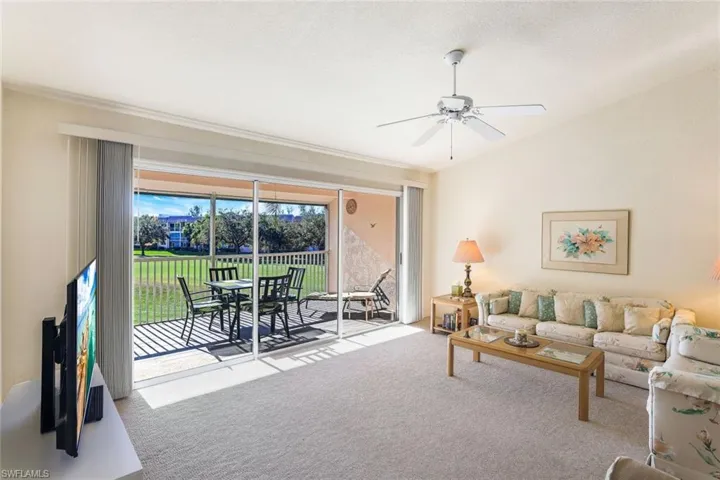 Carpeted living room with vaulted ceiling and ceiling fan