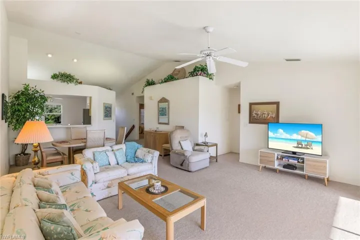 Carpeted living area featuring high vaulted ceiling and ceiling fan