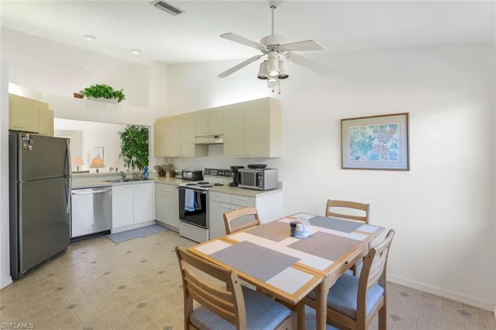 Kitchen featuring appliances with stainless steel finishes, light countertops, high vaulted ceiling, cream cabinetry, and under cabinet range hood