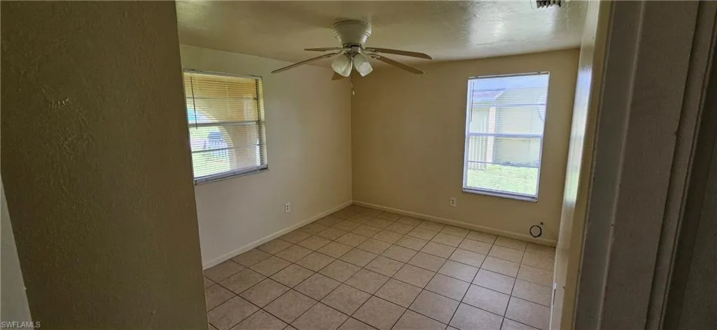 Unfurnished room featuring light tile patterned floors, ceiling fan, and a wealth of natural light