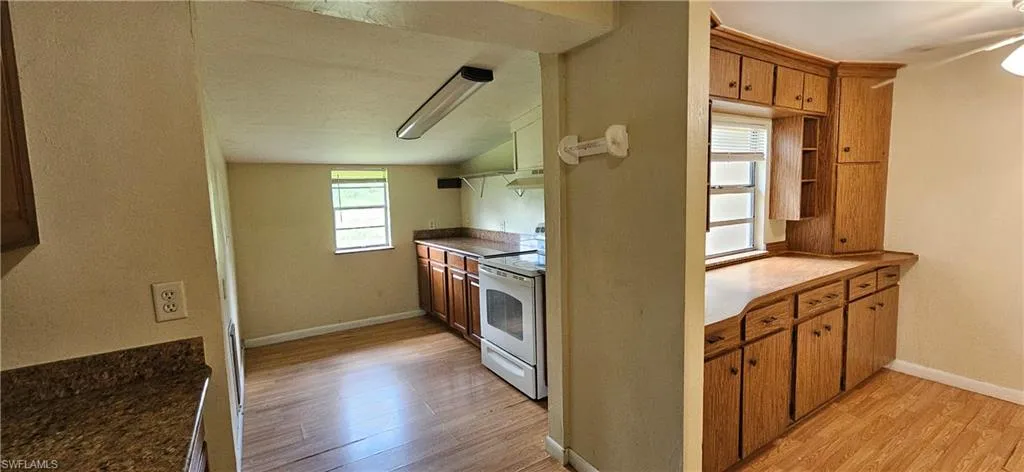 Kitchen featuring white electric range oven, light wood-type flooring, and lofted ceiling