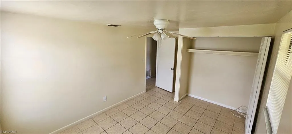 Unfurnished bedroom with ceiling fan, a closet, and light tile patterned floors