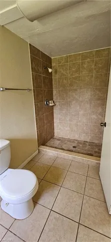 Bathroom featuring tiled shower, toilet, and tile patterned floors