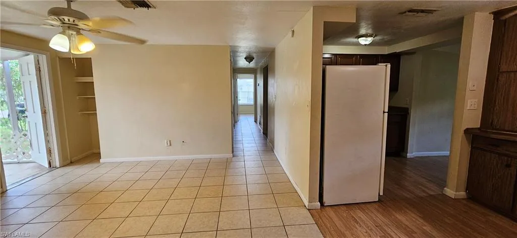 Empty room with ceiling fan, a textured ceiling, and light hardwood / wood-style flooring