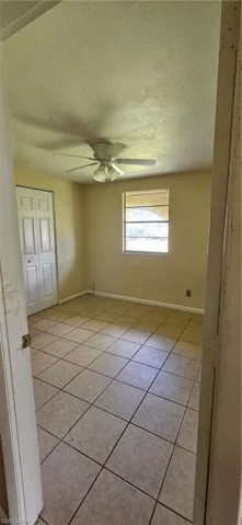 Unfurnished room with ceiling fan and light tile patterned floors