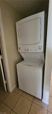 stacked washer / drying machine and light tile patterned floors