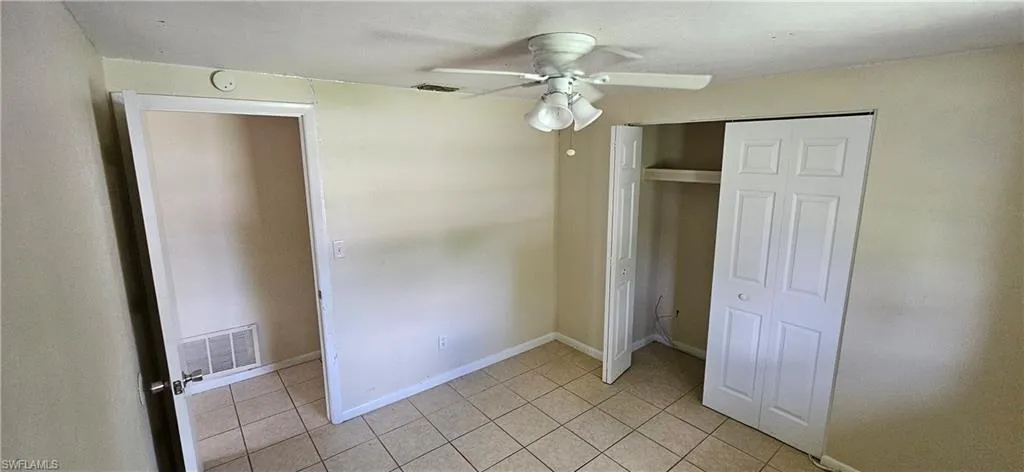 Unfurnished bedroom with light tile patterned flooring, ceiling fan, and a closet