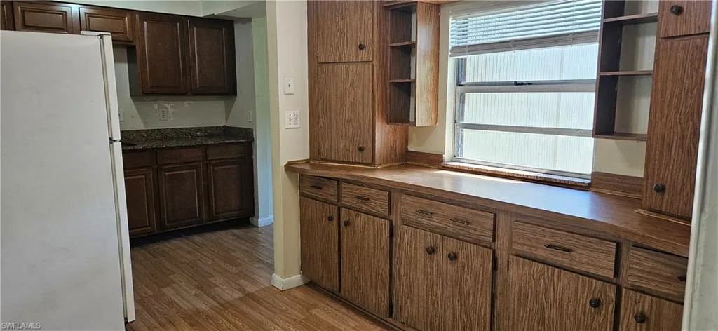 Kitchen with dark brown cabinetry, white refrigerator, and dark hardwood / wood-style flooring
