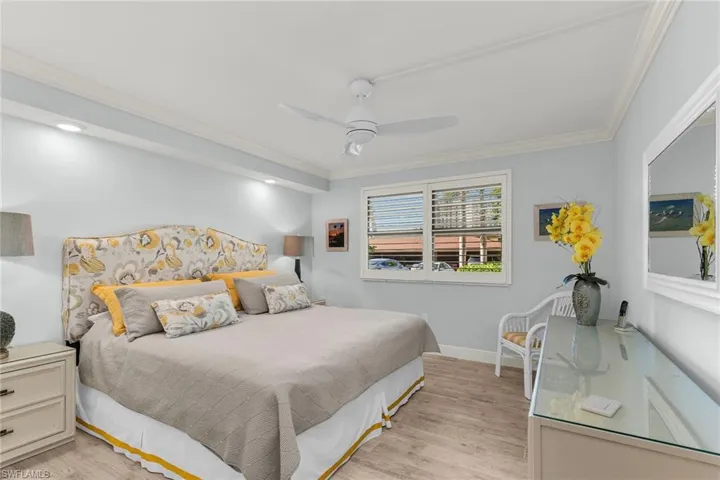 Bedroom with ceiling fan, baseboards, ornamental molding, and light wood finished floors