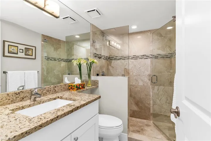 Full bathroom with visible vents, toilet, a stall shower, and vanity