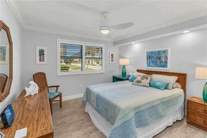 Bedroom featuring ceiling fan, light wood-type flooring, baseboards, and ornamental molding