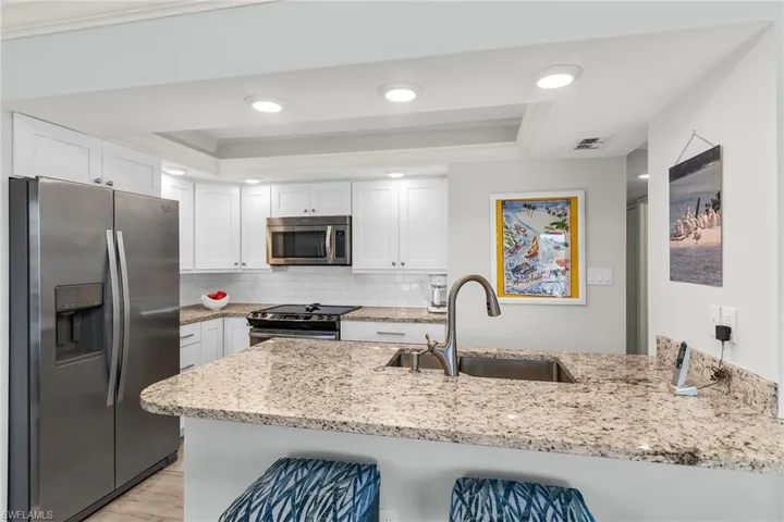 Kitchen featuring visible vents, appliances with stainless steel finishes, a tray ceiling, and a sink