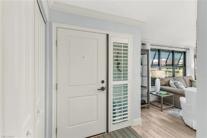 Foyer entrance with light wood-style floors and ornamental molding