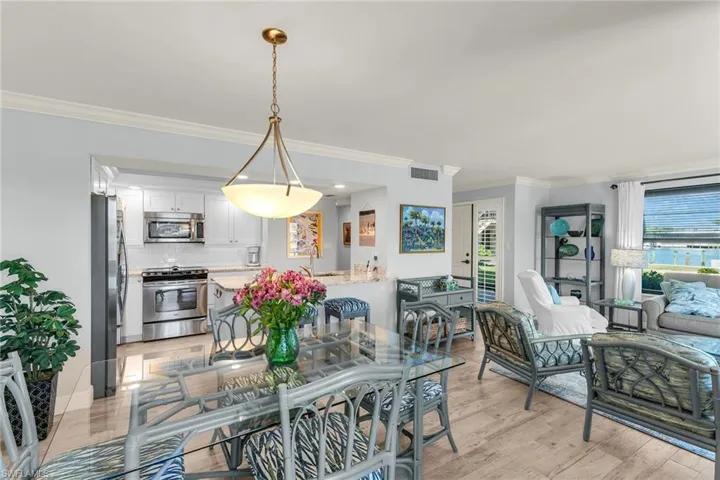 Dining area with light wood finished floors, visible vents, and ornamental molding