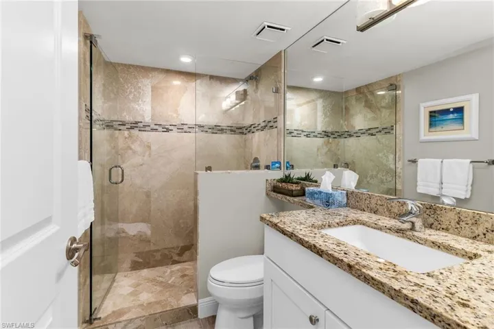 Bathroom featuring vanity, toilet, visible vents, and a stall shower
