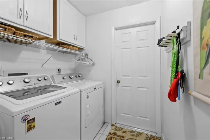 Laundry room with cabinet space, separate washer and dryer, and light tile patterned floors