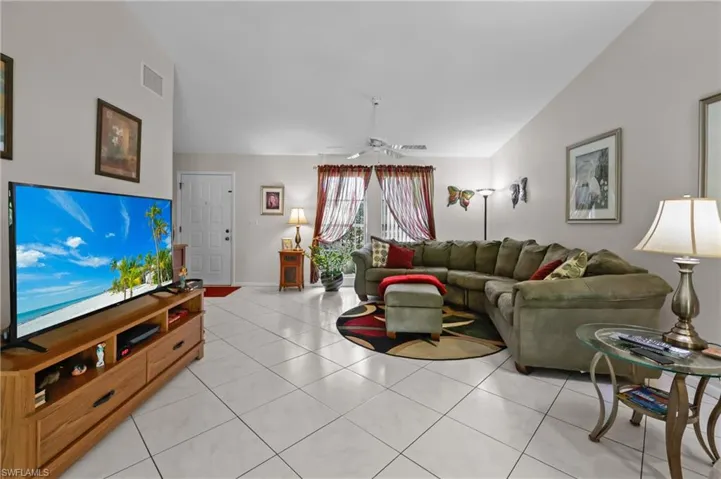 Living room with a ceiling fan, light tile patterned flooring, and baseboards