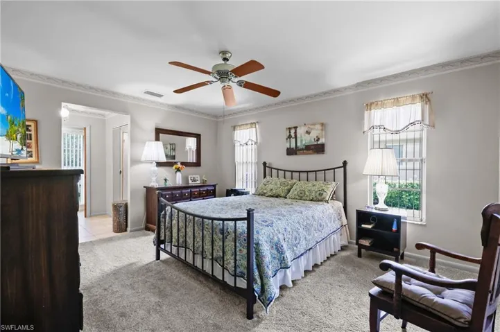 Bedroom featuring multiple windows, ornamental molding, light carpet, and baseboards