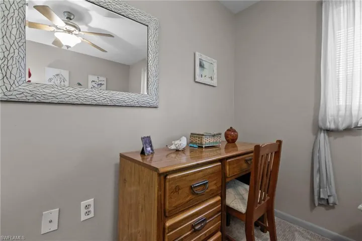 Carpeted office space with a ceiling fan and baseboards