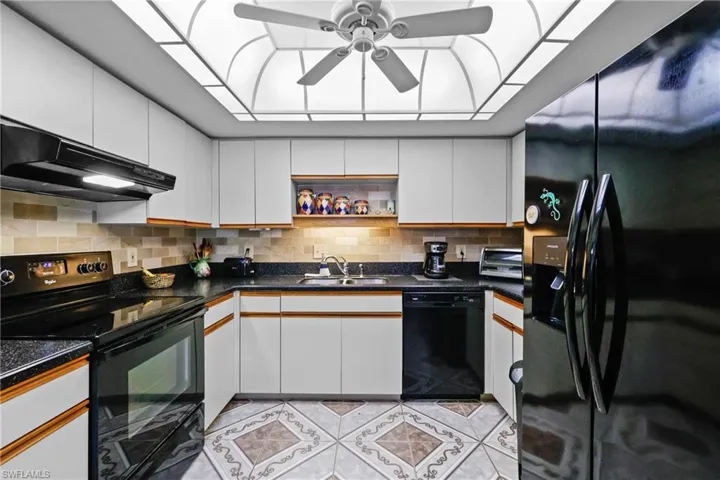 Kitchen with black appliances, extractor fan, a sink, ceiling fan, and white cabinetry