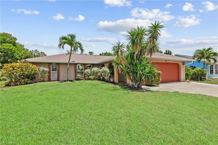 Ranch-style house featuring driveway, an attached garage, a front lawn, and stucco siding