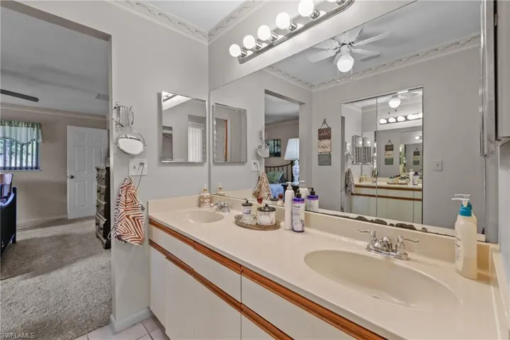 Full bathroom with ceiling fan, double vanity, ornamental molding, baseboards, and tile patterned flooring
