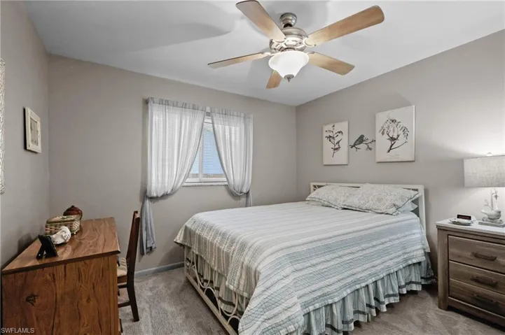 Carpeted bedroom with ceiling fan and baseboards