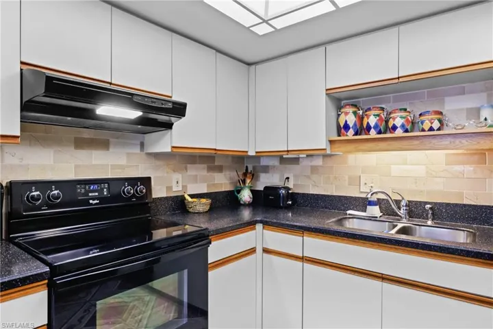Kitchen featuring electric range, extractor fan, a sink, white cabinets, and open shelves