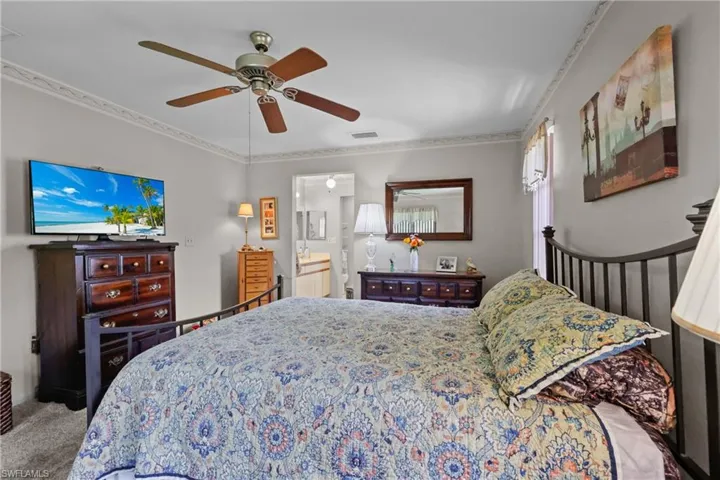 Bedroom featuring carpet floors, ornamental molding, a ceiling fan, and ensuite bathroom