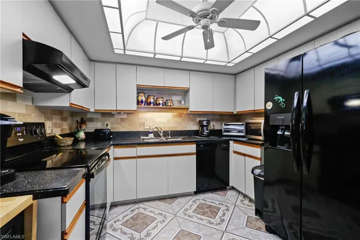 Kitchen featuring black appliances, extractor fan, a sink, and backsplash