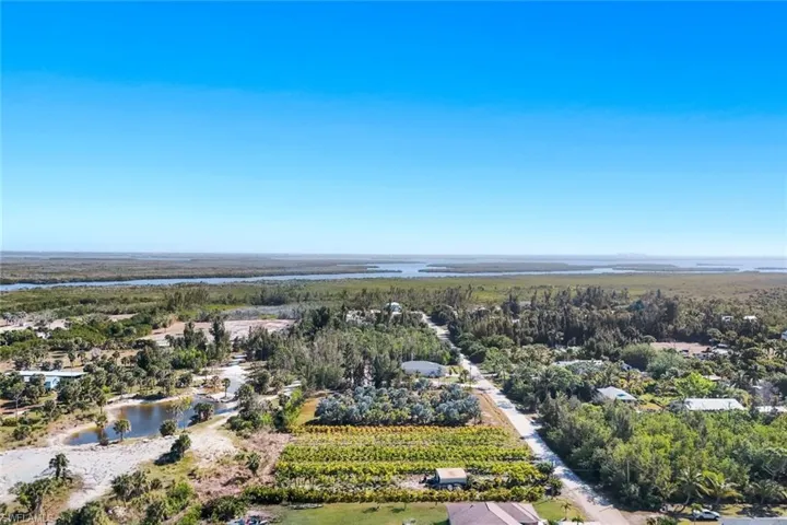 Aerial view of sparsely populated area with a nearby body of water and large plots for crops