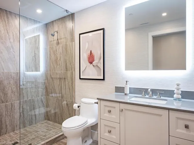 Bathroom with a tile shower, vanity, hardwood / wood-style flooring, and toilet