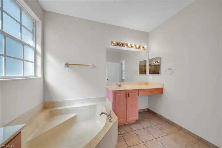 Full bathroom with vanity, a garden tub, and light tile patterned floors