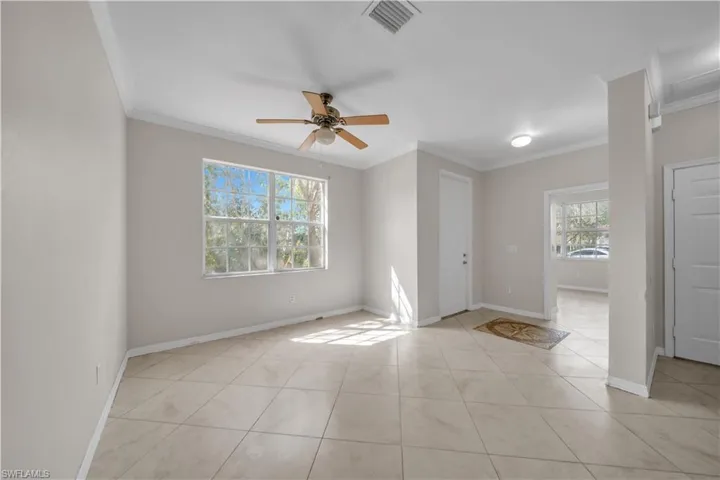 Unfurnished room with ceiling fan, ornamental molding, and light tile patterned flooring